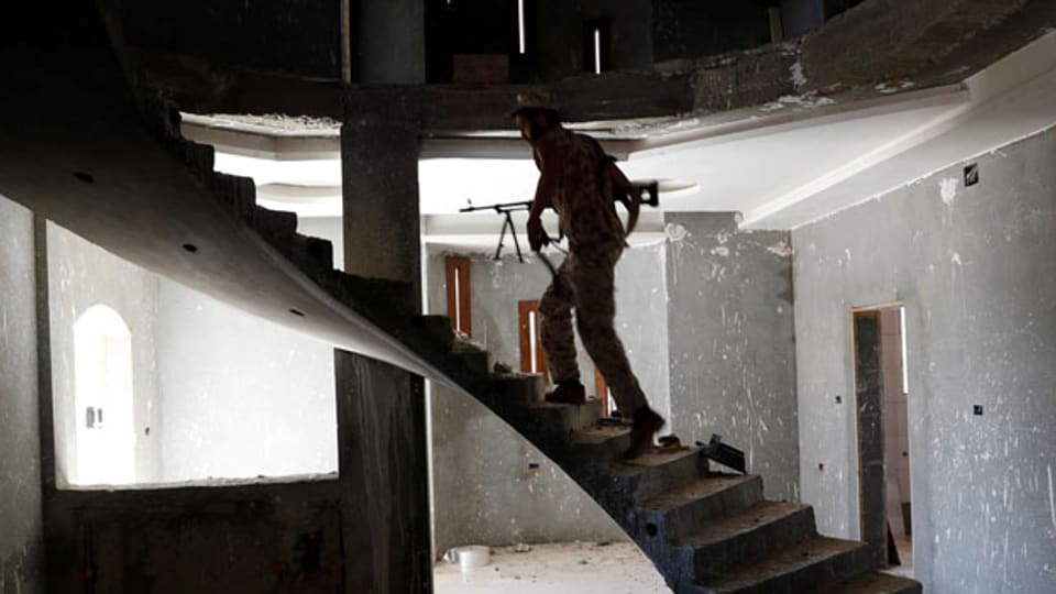 Ein Kämpfer mit Gewehr steigt in einem Haus in Tripolis die Treppen hoch.