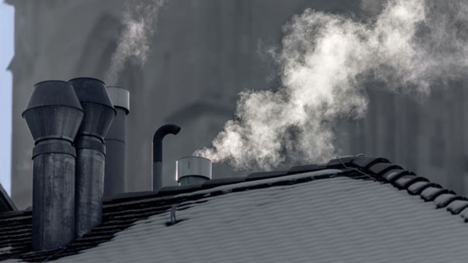 Rauch steigt aus Schornsteinen auf Hausdächern von Zürich,
