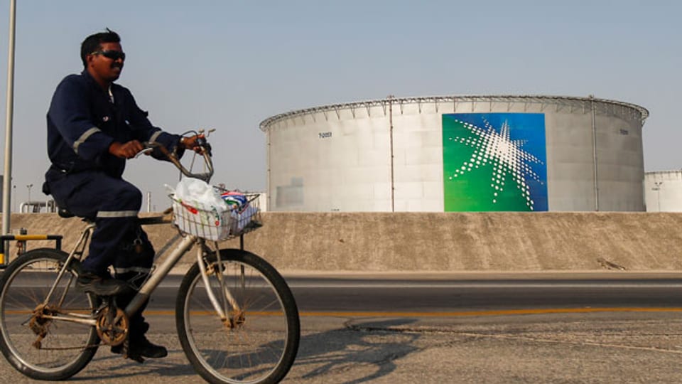Ein Mitarbeiter fährt mit dem Fahrrad neben Öltanks in der Ölfabrik Saudi Aramco in Abqaiq, Saudi-Arabien.