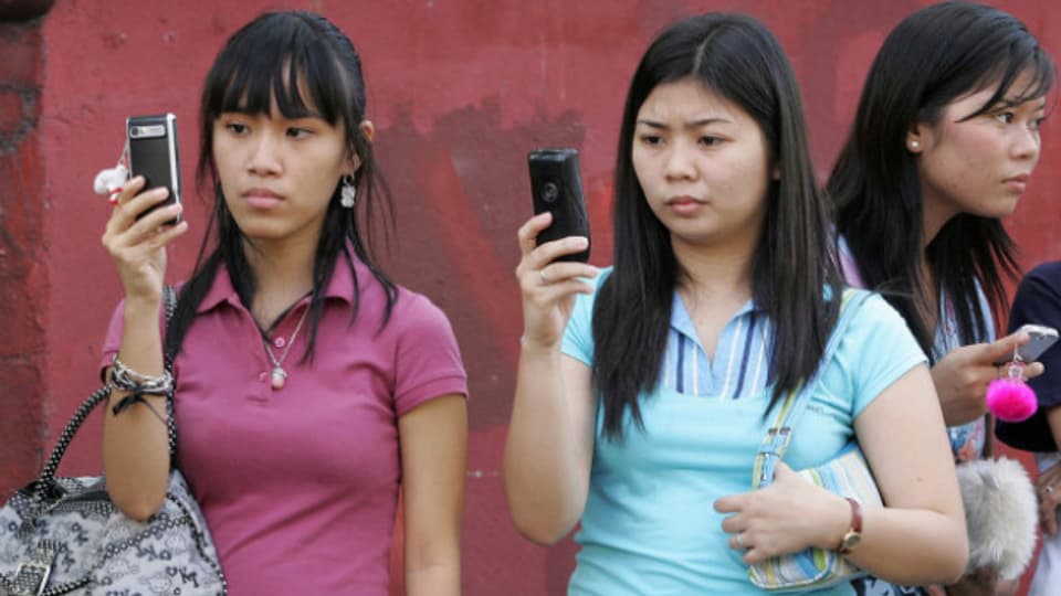 Frauen in Manila überweisen Geld auf dem Handy.