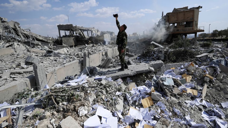 Ein syrischer Soldat filmt eine total zerbombte Siedlung.