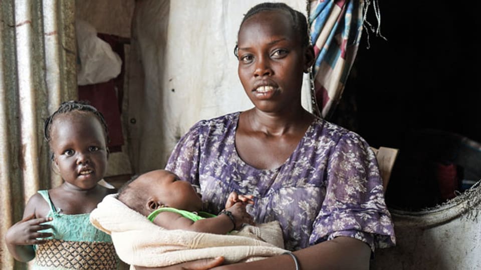 Nunu Tot sitzt mit ihrer frischgeborenen Tochter vor dem Zelt. Das Mädchen heisst Nyamal - übersetzt «Frieden».