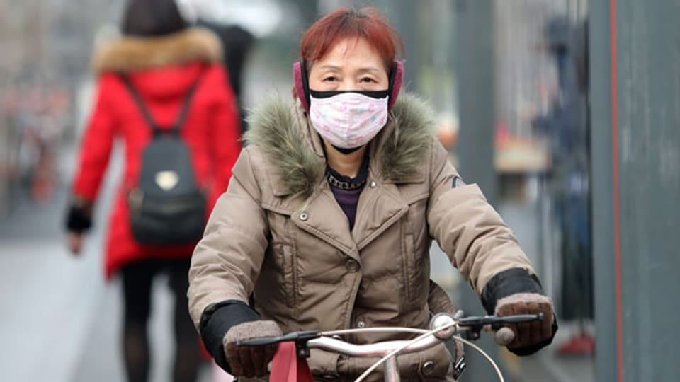 Eine chinesische Radfahrerin mit Maske in der Nähe des geschlossenen Huanan Seafood Wholesale Market, der mit Fällen eines neuen Coronavirus-Stammes in Verbindung gebracht wurde.