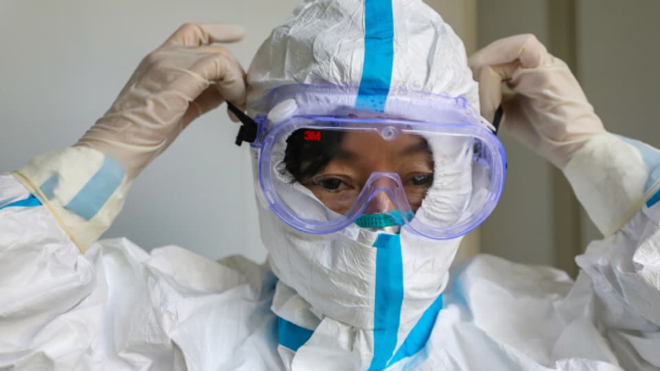 Ein Arzt in der chinesischen Stadt Wuhan zieht eine Schutzmaske über.