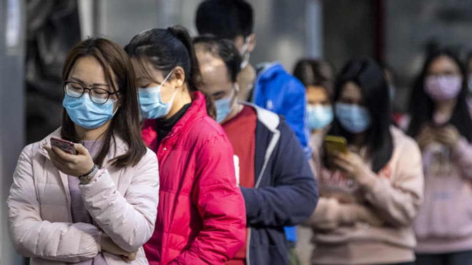Menschen in Guangzhou, China, stehen Schlange, um  Schutzmasken zu kaufen.
