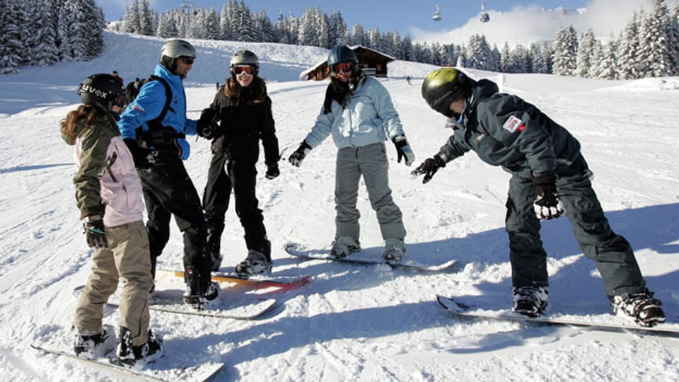 Eine Gruppe Teilnehmerinnen des Jugendskilagers (JUSKILA) lernen gemeinsam auf den frisch verschneiten Pisten in Lenk das Snowboarden.