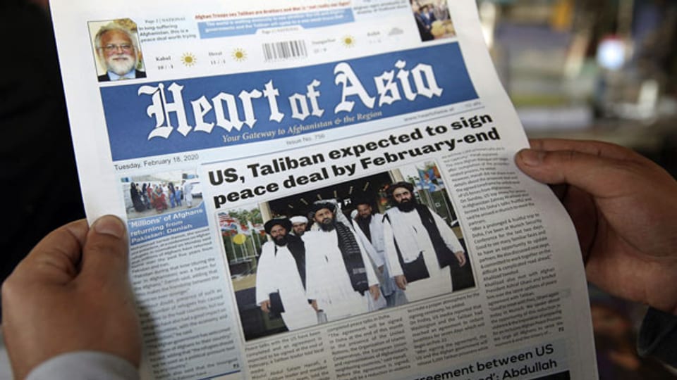 Ein Mann liest eine lokale Zeitung über Friedensgespräche in Kabul, Afghanistan.