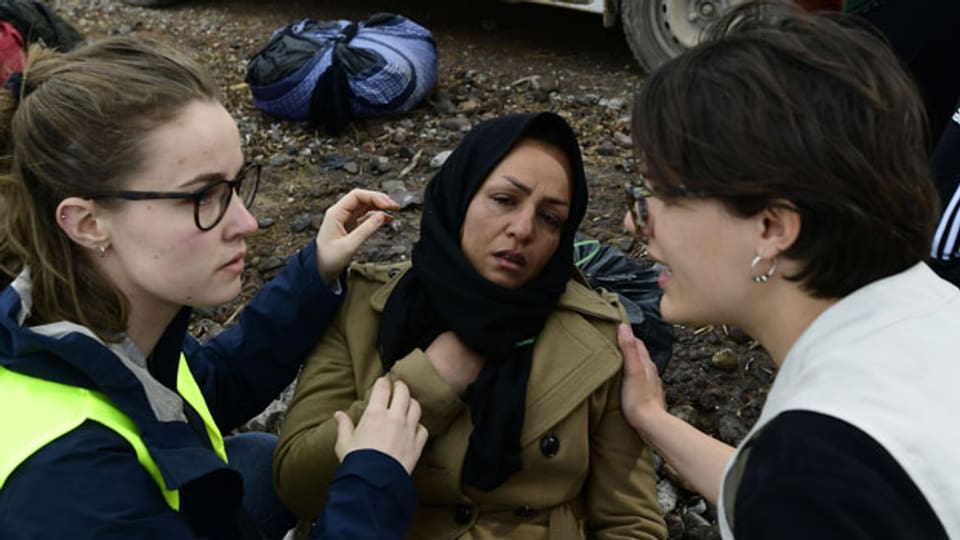 NGO-Mitglieder helfen einer Flüchtlingsfrau auf Lesbos.