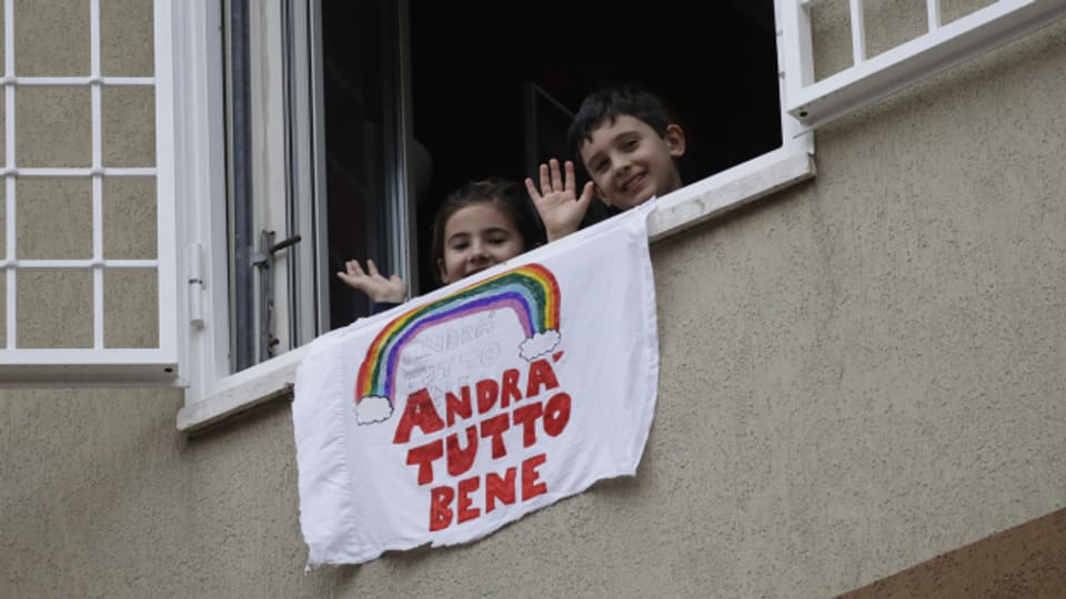 Zwei Kinder in Rom zeigen mit einem Plakat, dass es ihnen trotz Corona-Notstand gut geht.