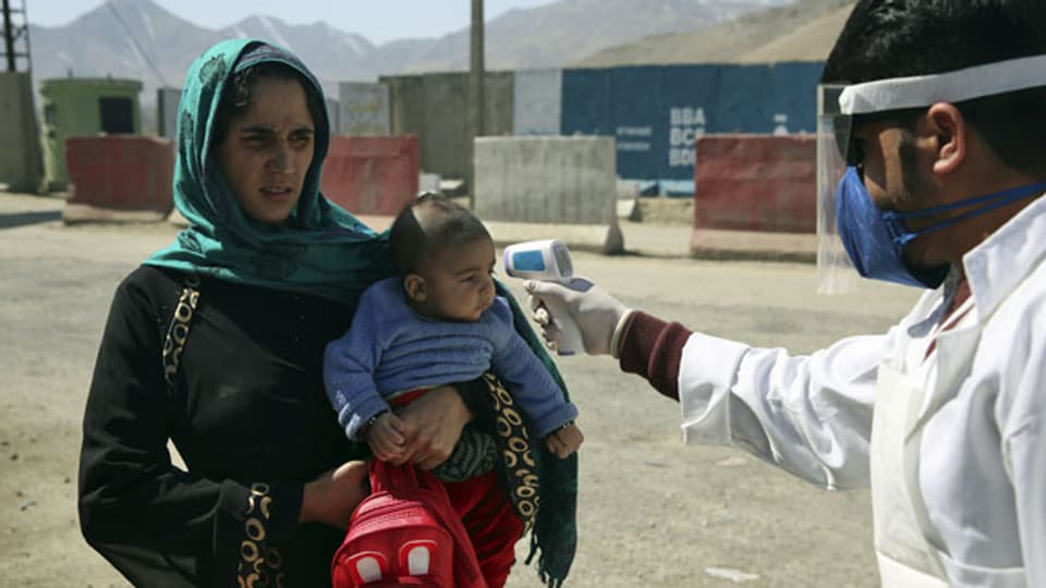 Ein afghanischer Gesundheitshelfer misst die Temperatur afghanischer Passagiere, um die Ausbreitung des Coronavirus zu verhindern.