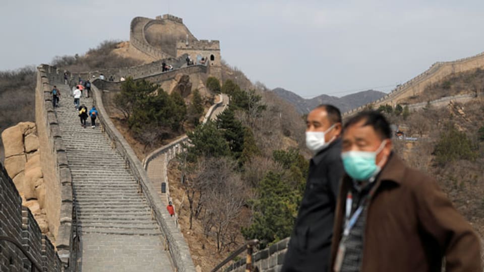 Männer mit Schutzmasken stehen auf der Chinesischen Mauer in Badaling in Peking am ersten Tag der Wiedereröffnung am 24. März 2020.