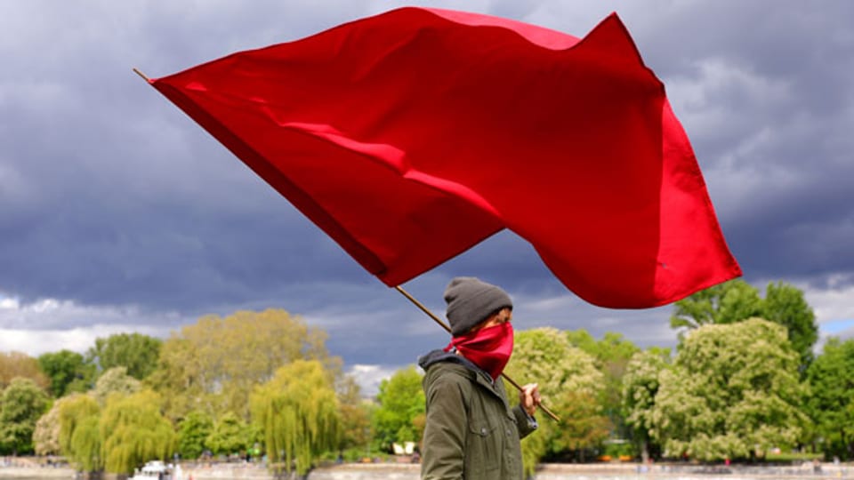 Eine Frau mit einer roten Fahne nimmt an einer Protestaktion am 1. Mai 2020 im Bezirk Kreuzberg in Berlin, Deutschland, teil.