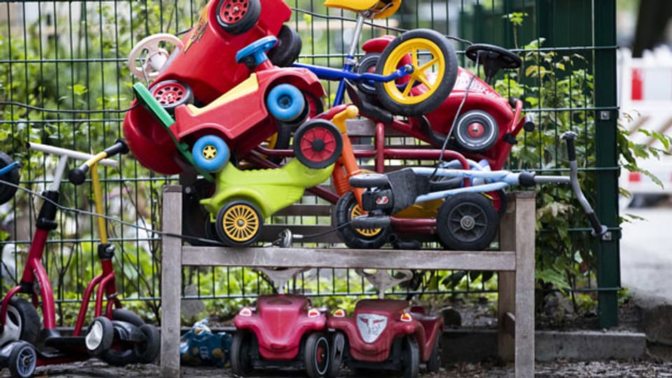 Ein Stapel Kindervelos und -fahrzeuge vor einer Kita.