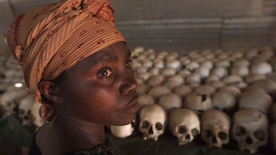 Eine Frau vor Schädeln von Völkermord-Opfern in Kigali