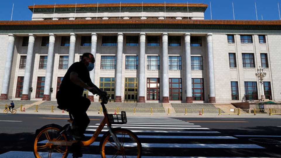 Ein Velofahrer fährt an der Grossen Halle des Volkes vorbei, dem Veranstaltungsort des bevorstehenden Nationalen Volkskongresses in Peking.