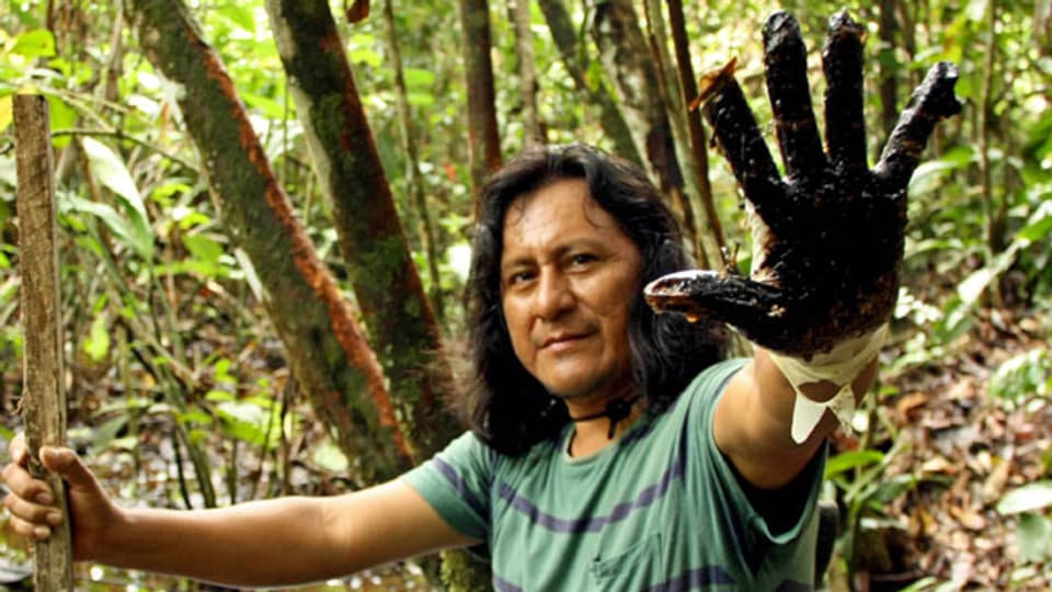 Ermel Chaves steht mit erdölverschmierter Hand an einem Wasserlauf im Regenwald im Nordosten Ecuadors.