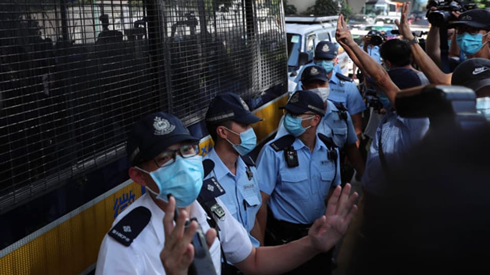 Polizisten halten Wache, während der pro-demokratische Protestler Tong Ying-kit, 23, das Gericht verlässt.