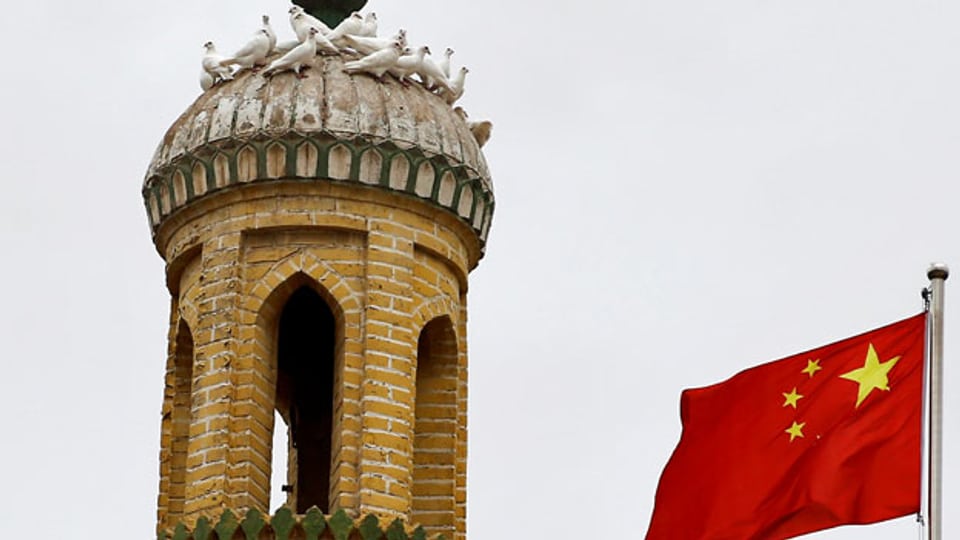 Chinesische Flagge vor dem Minarett der Id Kah-Moschee in Kaxgar, Xinjiang. In beiden Ländern nehmen Konflikte entlang ethnischer und religiöser Linien zu.