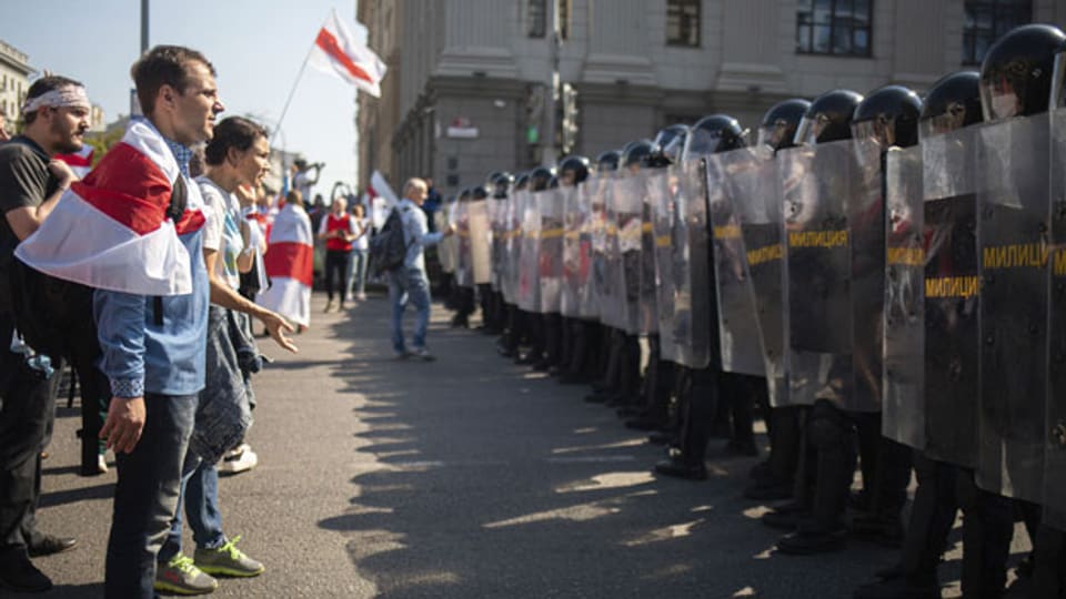 Weissrussische Oppositionsanhänger stehen während einer Kundgebung in Minsk, Belarus, am 30.8. 2020, vor einer Polizeikolonne.