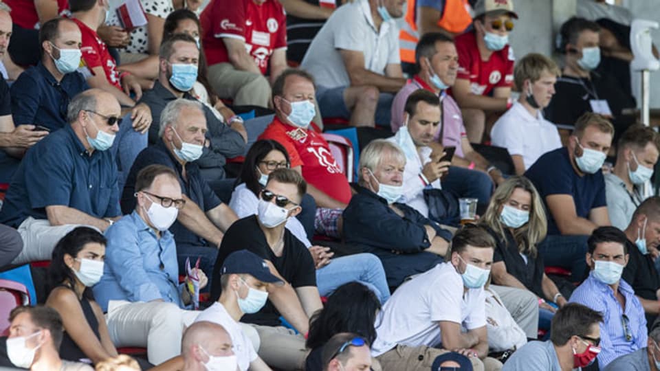 Zuschauer mit Atemschutzmasken verfolgen das Schweizer Fussball Cup 1/4-Final zwischen dem FC Rapperswil-Jona und dem FC Sion im Stadion Grünfeld am 6. August 2020 in Rapperswil-Jona.