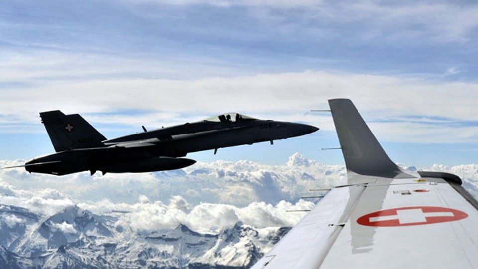 Eine FA18 Hornet der Schweizer Armee fliegt neben einem Zivilflugzeug während einer Luftpolizeiübung.