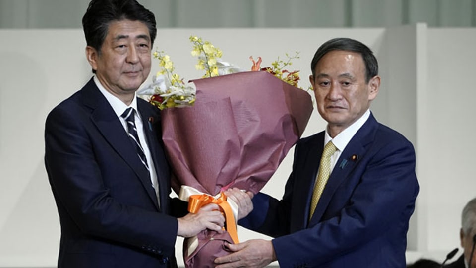 Japans Premierminister Shinzo Abe (li.), erhält Blumen von Kabinettschef Yoshihide Suga, nachdem Suga bei den Führungswahlen der Liberaldemokratischen Partei (LDP) zum neuen Chef der Regierungspartei Japans gewählt wurde.