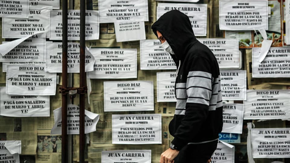 Ein Mann geht in Buenos Aires, Argentinien, an einem Geschäft mit Transparenten gegen Niedriglöhne vorbei.