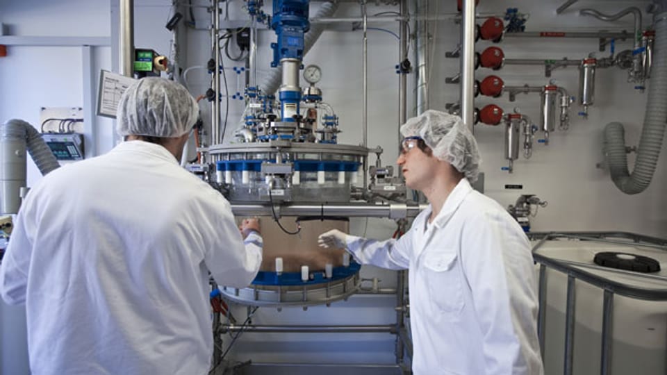 Zwei Mitarbeiter arbeiten an einer Maschine zur Herstellung von Wirkstoffen beim Biochemie-Unternehmen Bachem Group Inc. in Bubendorf, BL.