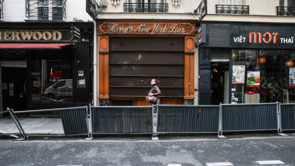 Eine Frau mit Maske vor einer geschlossenen Bar in Paris.