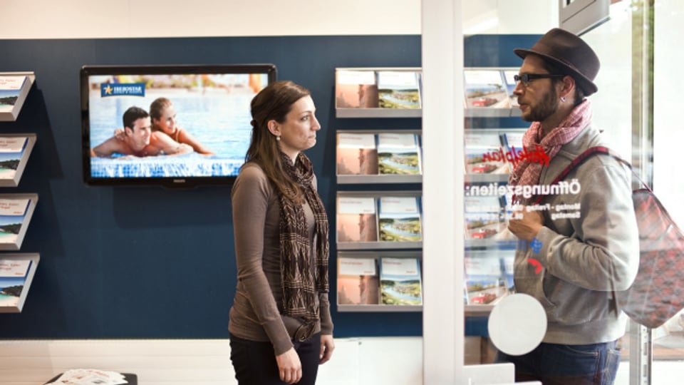Eine Hotelplan-Mitarbeiterin begrüsst im Reisebüro in Zuerich-Oerlikon einen Kunden