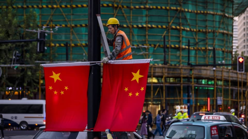 Ein Mann entfernt chinesische Nationalflaggen in Schanghai.