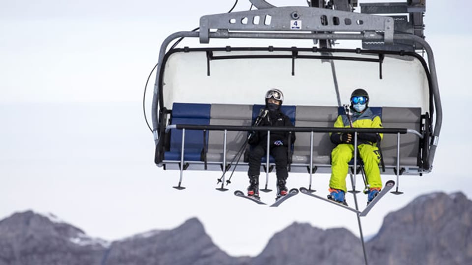 Skifahrer mit Atemschutzmaske fahren mit dem Sessellift «Ice Flyer» auf dem Titlis, am 10. November 2020. Auf allen Sesselbahnen, Skiliften und Seilbahnen des Skigebietes gilt Maskenpflicht.