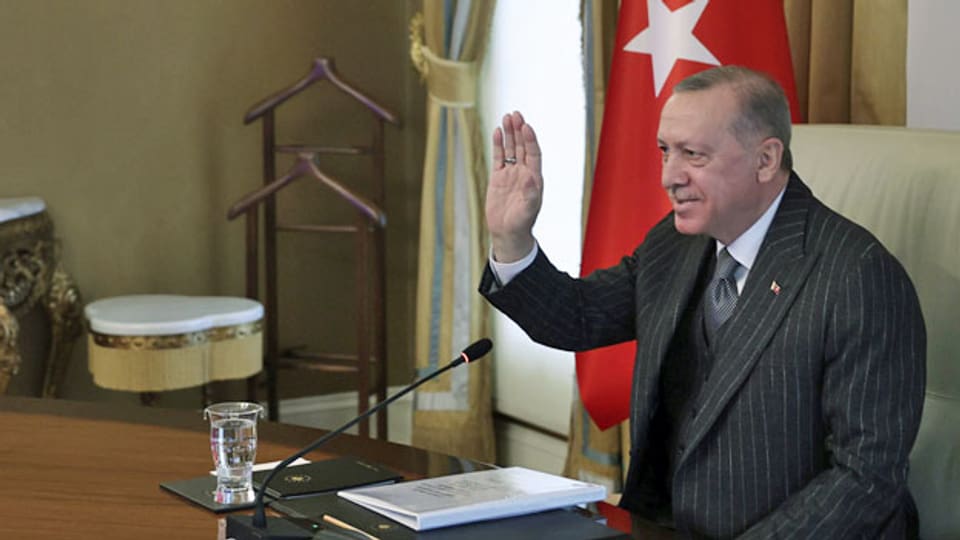Der türkische Präsident Recep Tayyip Erdogan winkt an einer Videokonferenz in die Kamera.