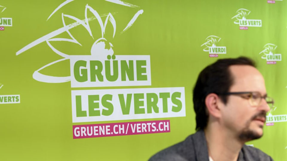 Logo der GPS, Grüne Partei der Schweiz, fotografiert hinter Balthasar Glättli, Nationalrat und Parteipräsident.