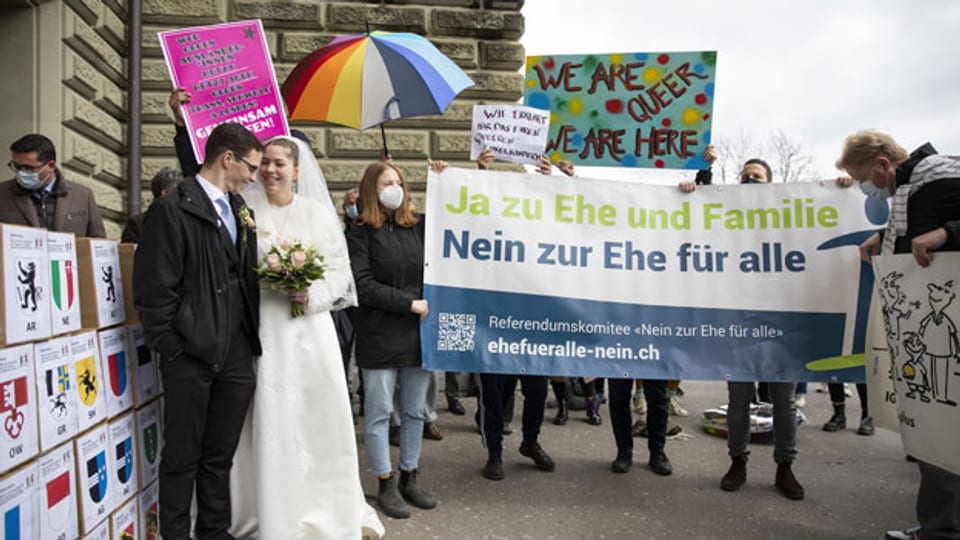 Demonstranten (hinten) protestieren bei der Einreichung der Unterschriften für das Referendum «Nein zur Ehe für alle» am 12. April 2021 in Bern.