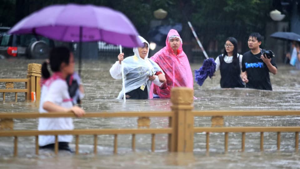 Menschen waten durch überschwemmte Strassen in Zhengzhou in der zentralchinesischen Provinz Henan am 20. Juli 2021.