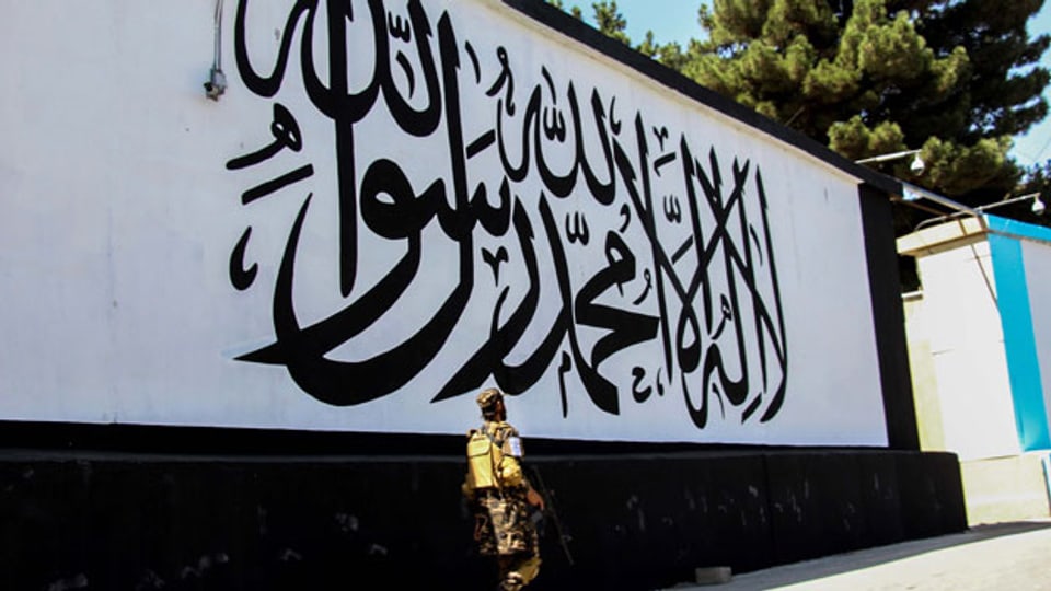 Taliban stehen vor dem Gebäude der ehemaligen US-Botschaft Wache, während die Wand mit der arabischen Aufschrift «Es gibt keinen Gott ausser Allah, Mohammed ist der Gesandte Allahs» in Kabul, Afghanistan, am 8. September 2021, bemalt ist.