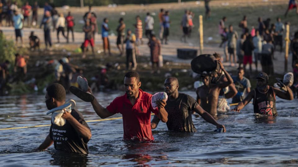 Migrantinnen und Migranten überqueren einen Fluss in der texanischen Grenzstadt Del Rio.