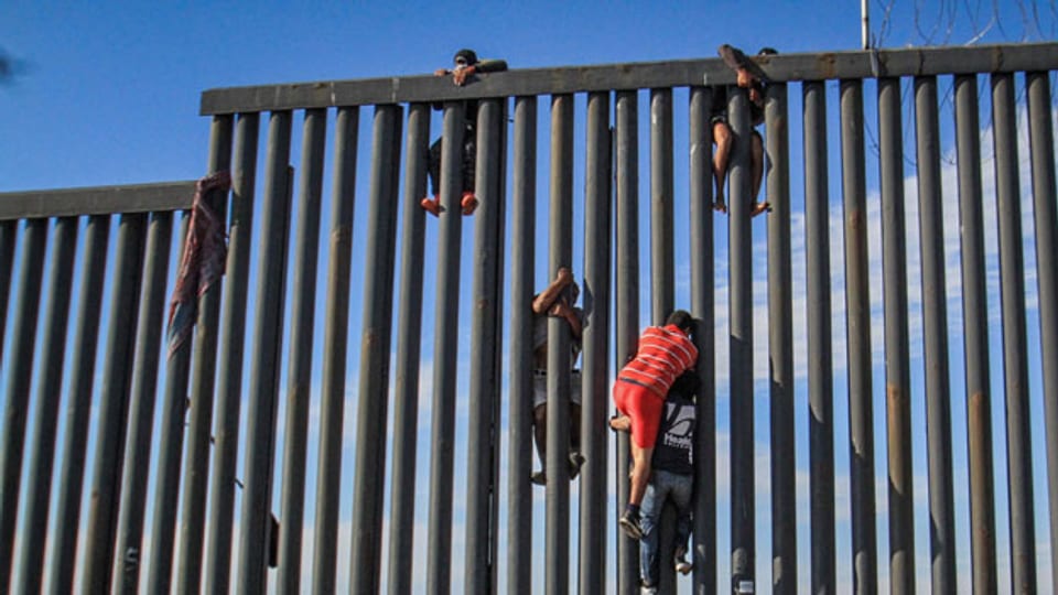 Migranten übersteigen die Mauer zwischen Texas und den USA.