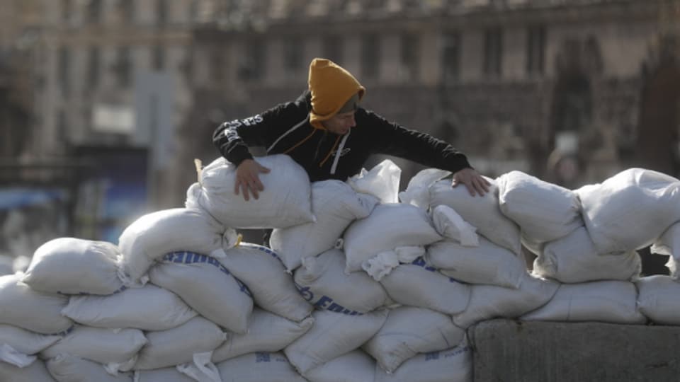 Ein Mann errichtet eine Absperrung aus Sandsäcken in der Innenstadt von Kiew.