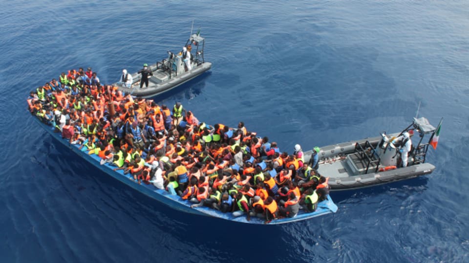 Ein vollkommen überladenes Flüchtlingsboot auf hoher See.