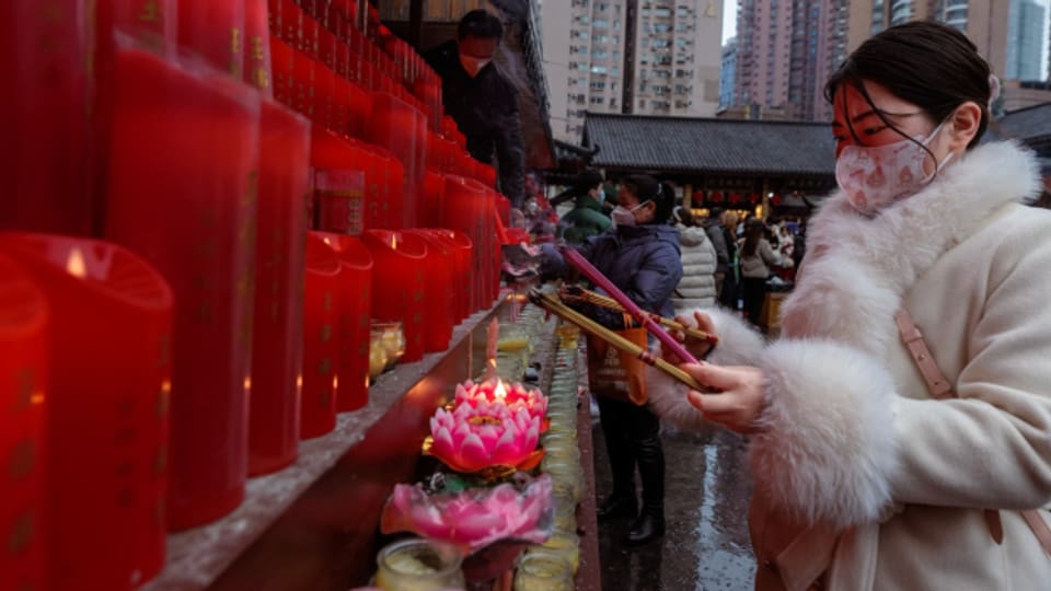 In einem buddhistischen Tempel in Shanghai zündet eine Frau Rächerstäbchen an.