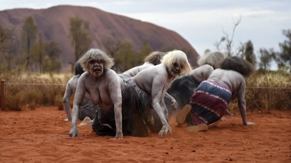 Aboriginal-Frauen führen vor dem Berg Uluru (Ayers Rock) einen traditionellen Tanz auf.