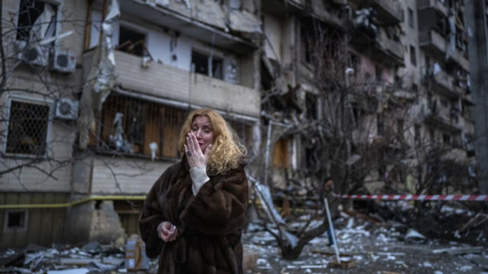 Eine Frau neben ihrem Wohnhaus in Kiew, das von russischen Raketen getroffen wurde.