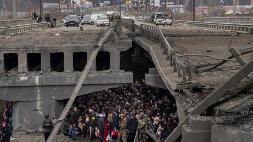 Ukrainerinnen und Ukrainer drängen sich unter einer zerstörten Brücke, als sie versuchen, über den Fluss Irpin in einem Aussenbezirken von Kiew zu fliehen.