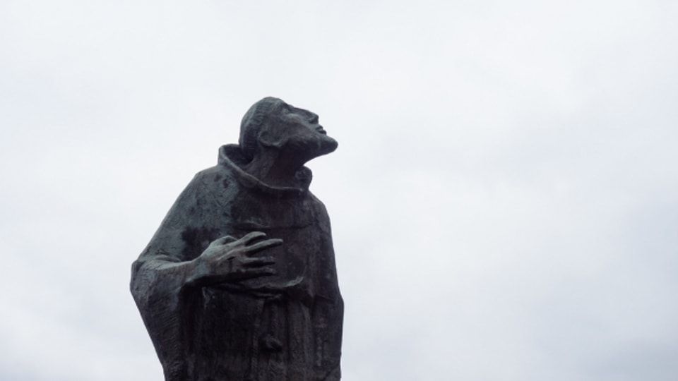 Graue Wolken ziehen über eine Statue des Heiligen Franz von Assisi im bayrischen Bad Staffelstein. Dort beginnt am Montag die Frühjahrs-Vollversammlung der Deutschen Bischofskonferenz.