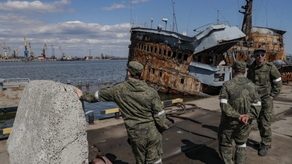 Russische Soldaten in Mariupol vor einem versenkten ukrainischen Marineboot.