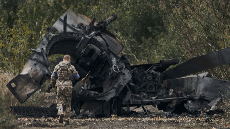 Ein ukrainischer Soldat begutachtet einen zerstörten russischen Panzer in der Region Charkiw (11.09.22).