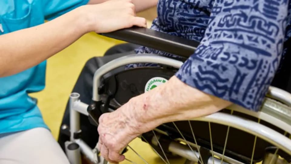Eine Pflegekraft betreut eine ältere Frau im Rollstuhl (Symbolbild).