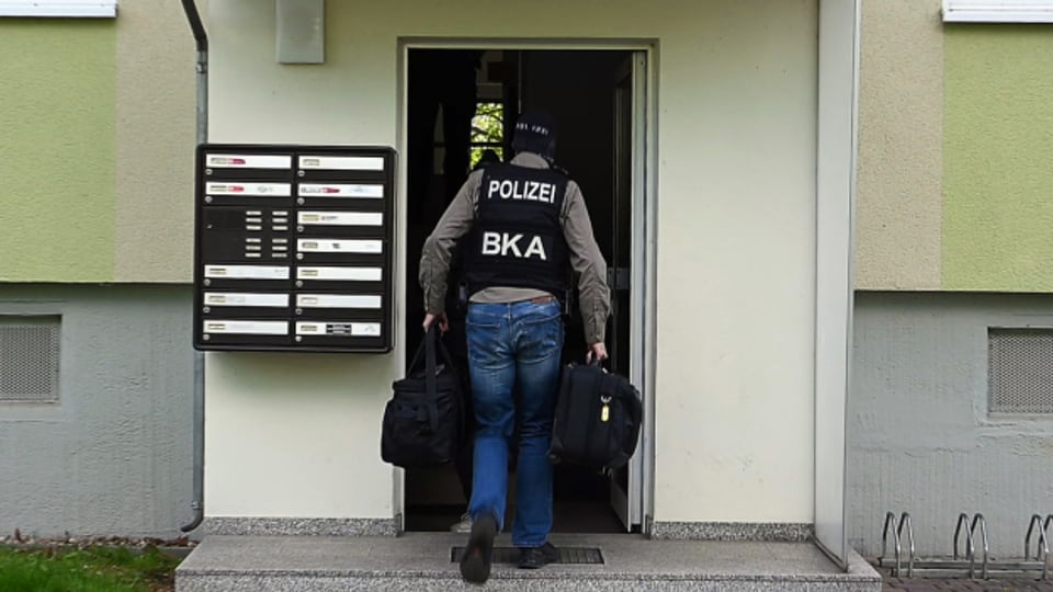 Polizisten gehen in das Treppenhaus eines Wohnhauses. Ein Mitarbeiter des deutschen Europaabgeordneten ist in Dresden wegen des Verdachts der Spionage für China festgenommen worden.